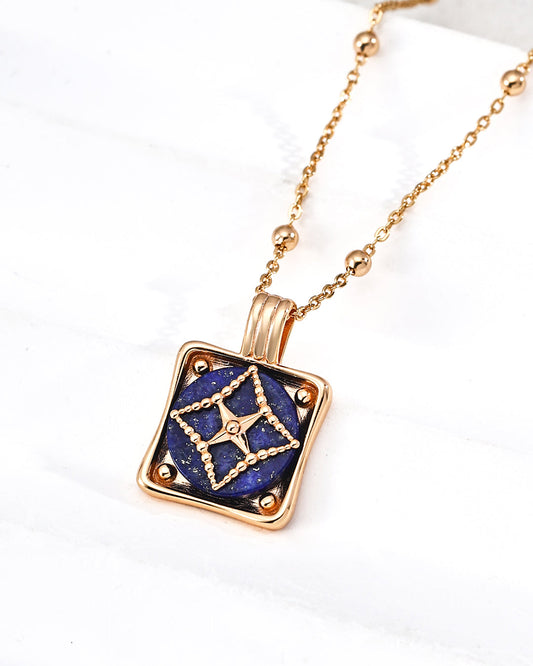 Gold necklace with a blue pendant on a white background