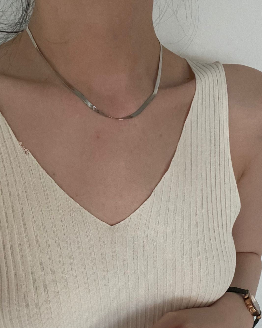 Person wearing a beige ribbed tank top against a plain background