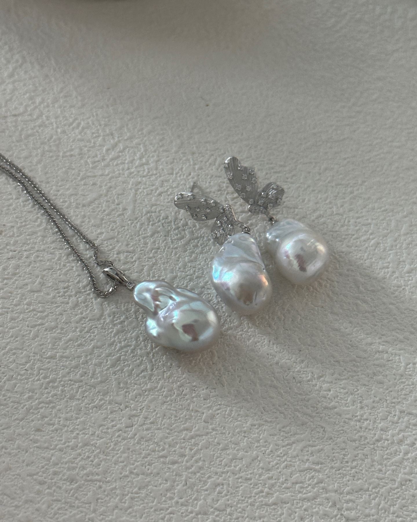Pearl necklace and earrings on a textured surface