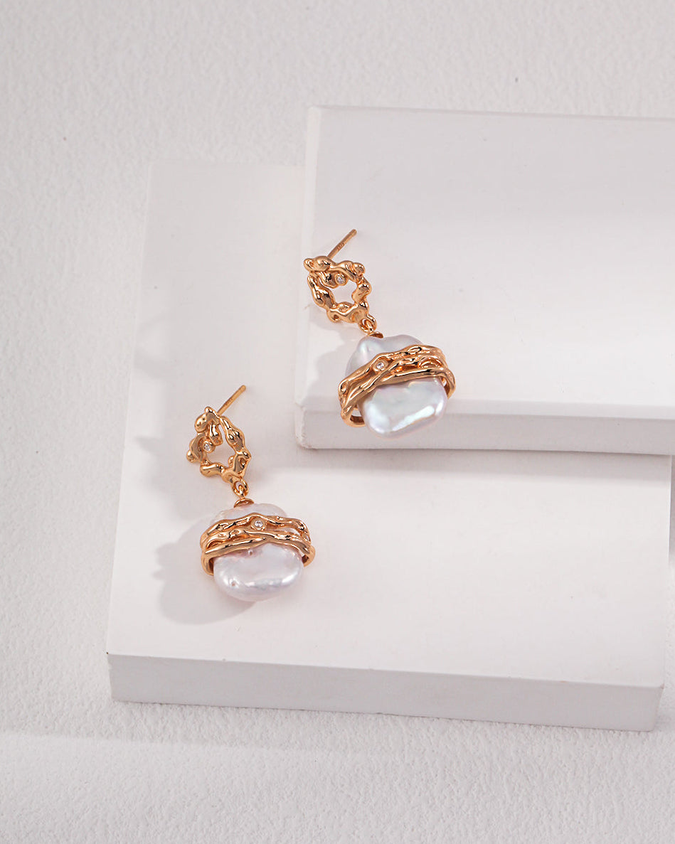 Pair of gold earrings with clear stones on a white surface