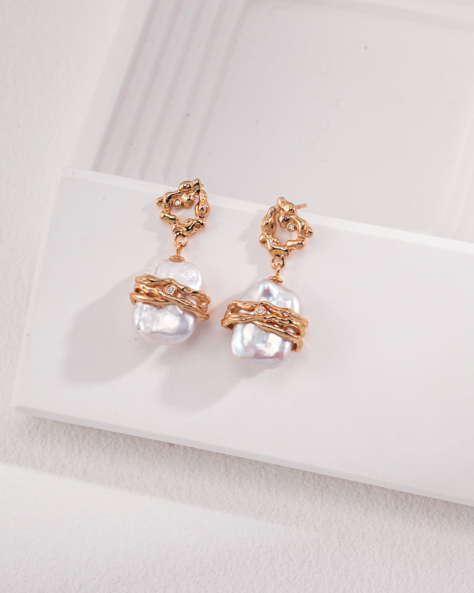 Pair of pearl earrings with rose gold accents on a white surface