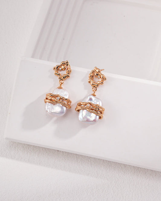 Pair of pearl earrings with rose gold accents on a white surface