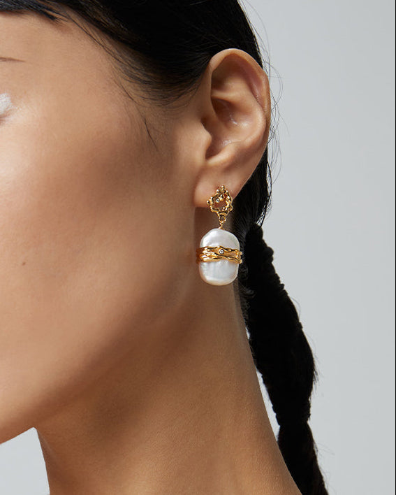 Woman wearing gold necklace and earrings against a neutral background