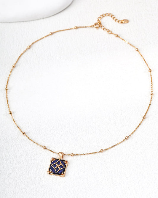 Gold necklace with a blue pendant on a white background