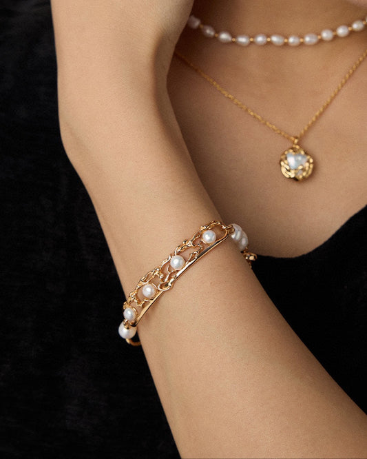 Pearl bracelet and necklace on a person against a neutral background