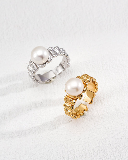 Two pearl rings, one silver and one gold, on a white background
