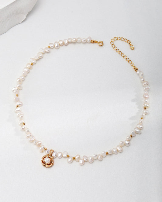 Pearl necklace with gold clasp on a light gray background