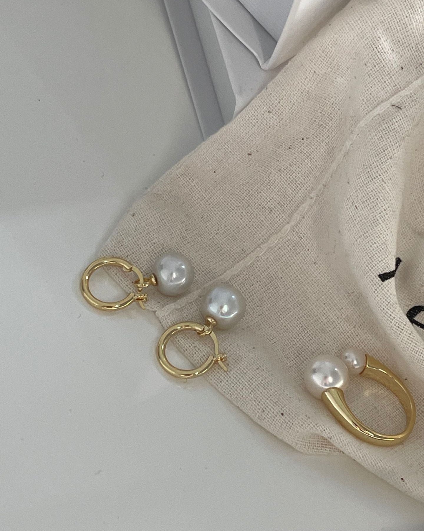 Gold earrings with pearls on a light background