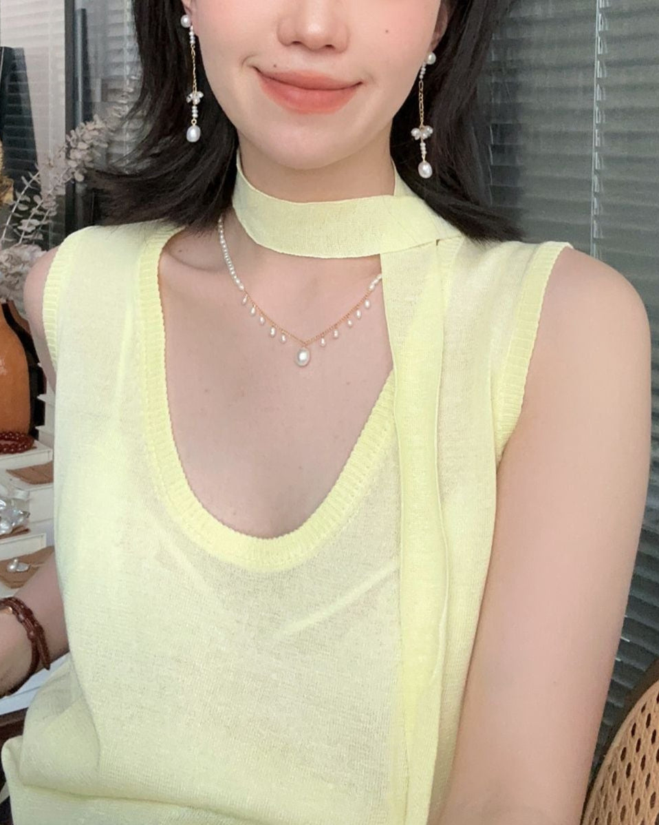 Woman wearing a light green sleeveless top with a blurred background