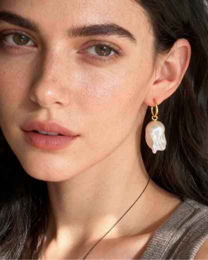 Close-up of a woman wearing pearl earrings with a neutral background
