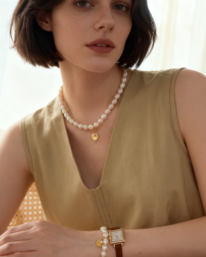 Woman wearing a green sleeveless top and pearl necklace with a blurred background