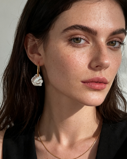 Woman wearing pearl earrings and necklace against a neutral background