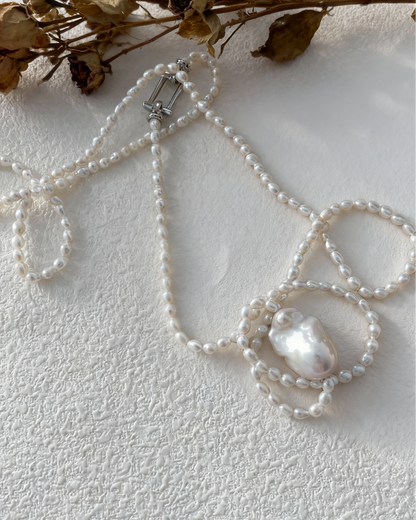 Pearl necklace with decorative elements on a textured white surface